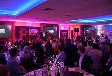 Running industry awards ceremony with attendees in formal attire, stage setup, and vibrant lighting, celebrating achievements in the running and athletics community.