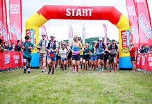 Runners start the Peak District Ultra Challenge at the starting line under a red and yellow inflatable arch.
